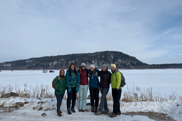 Six hikers pose and smile on a snowy winter day. Photo provided by: Lisa Szela.